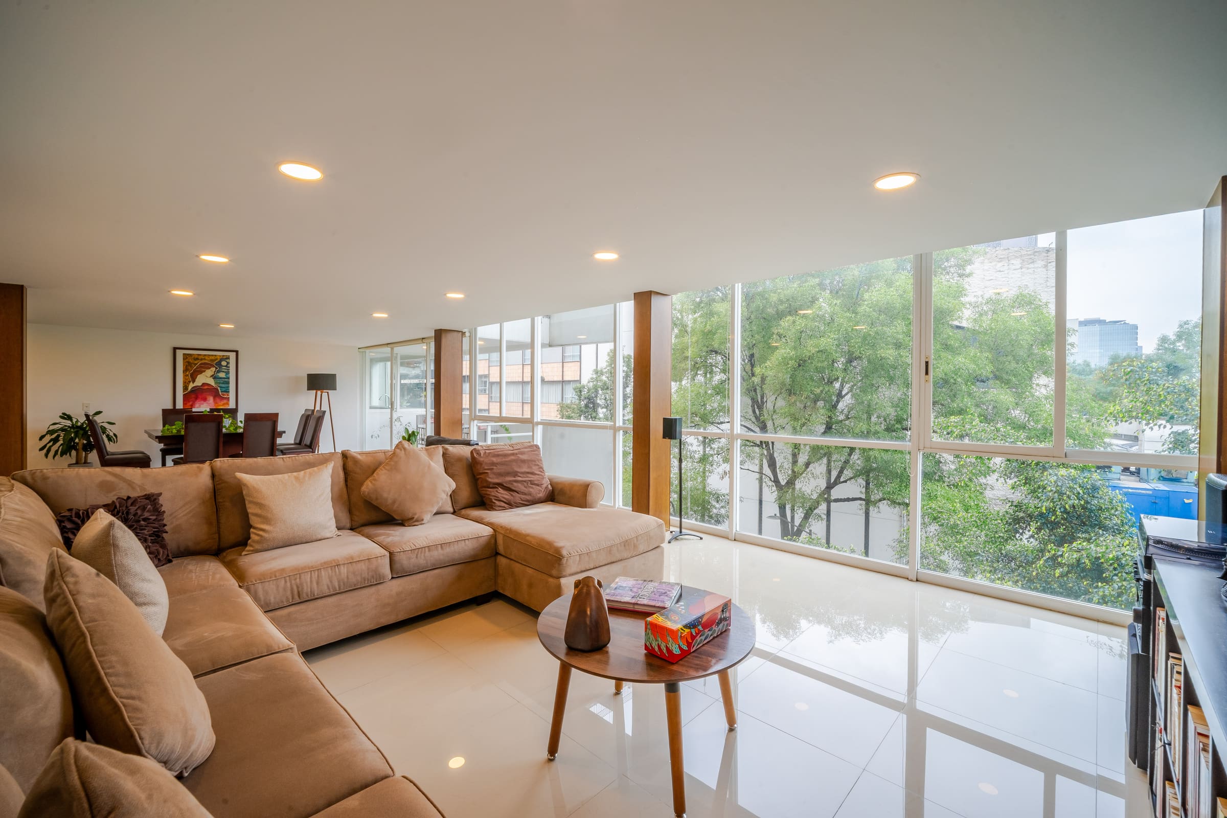 Sala con ventanal de piso a techo hacia los árboles de la calle Sócrates