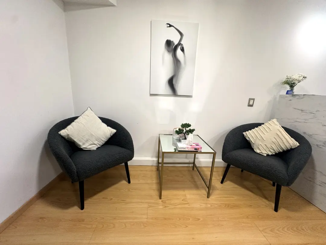 Sala de espera con dos sillones gris oscuro y mesa de centro